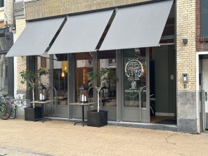 De restaurantgevel met donkere markiezen en het De Betere Tijden-logo op de ramen.