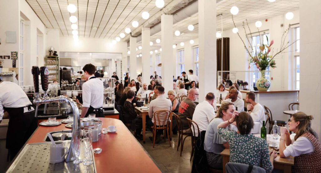 Levendige lichte eetzaal met witte pilaren en lange bar.
