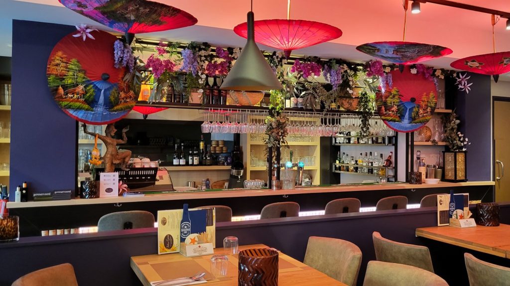 Kleurrijk interieur met bar, decoratieve parasols en eettafels.