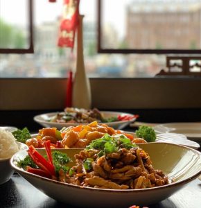 Chinese gerechten op een tafel met traditioneel interieur op de achtergrond.