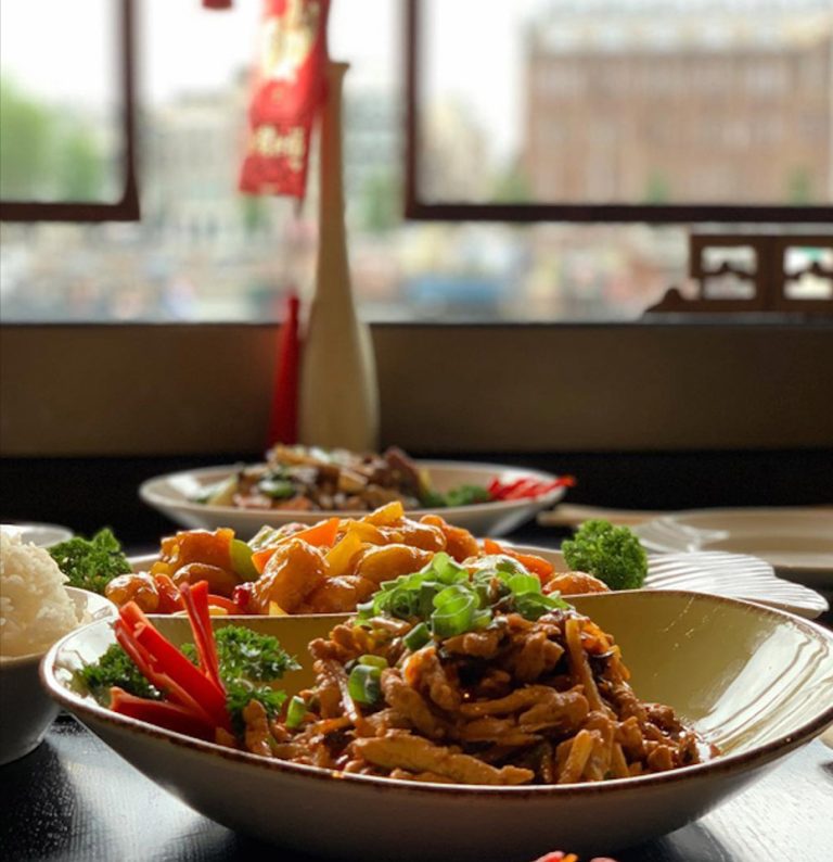 Chinese gerechten op een tafel met traditioneel interieur op de achtergrond.