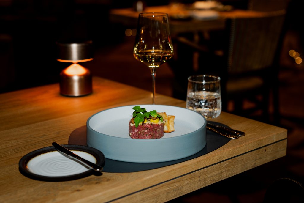 Opmaak van gerecht op gedekte tafel in het donkere NY Basement-interieur.