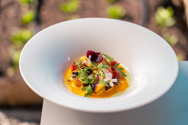 Gerecht met kruiden en bloemen in een diepe witte kom.