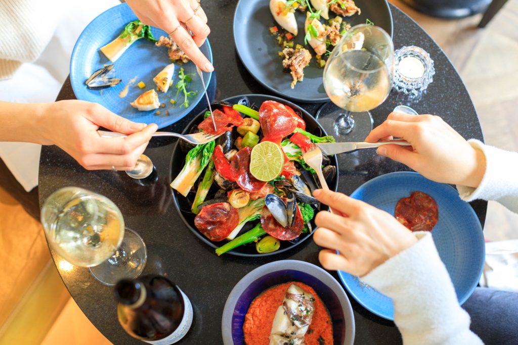 Bovenaanzicht van tapas, schaal- en schelpdieren en wijn op restauranttafel.