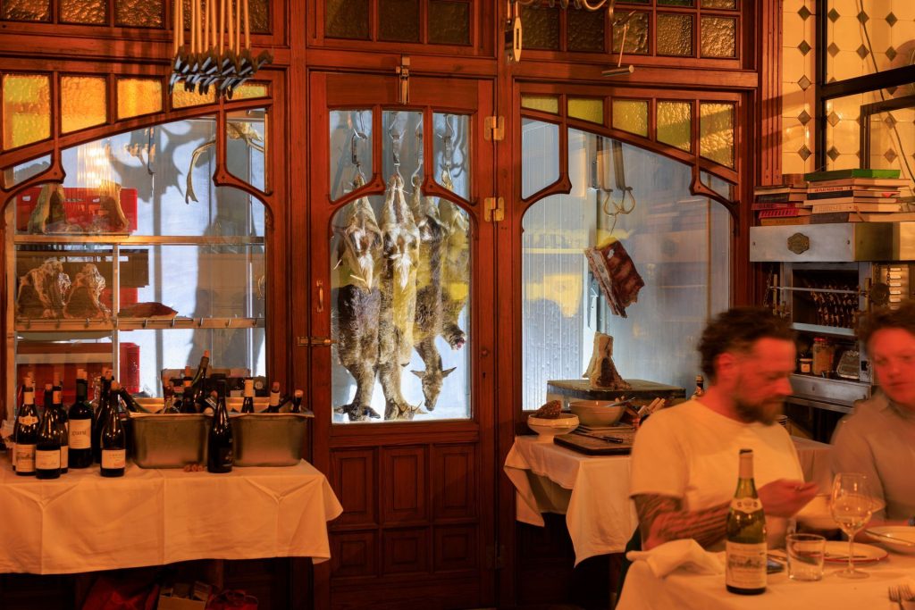 Restaurantinterieur met houten ornamenten en gedekte tafels.