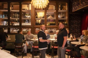 Levendig restaurantinterieur met gasten en medewerkers.