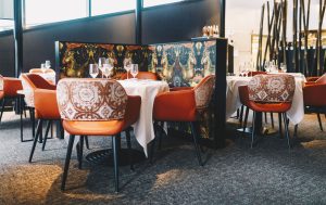 Kleurrijke stoelen en gedekte tafels in restaurantzaal.