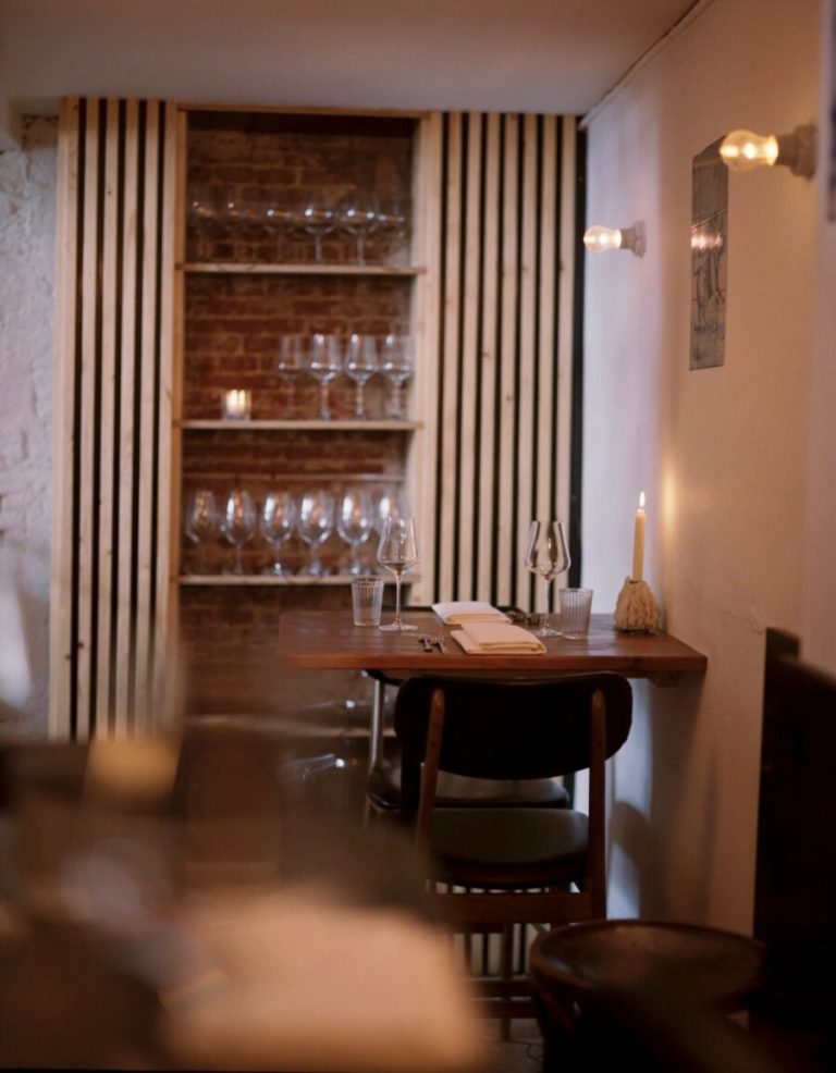 Warme nis met ronde tafel en glazenrek in restaurant Watergang.