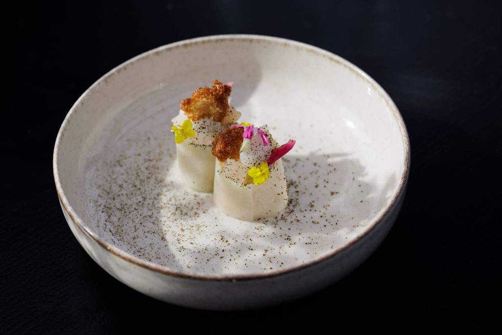 Klein verfijnd gerecht met bloemen in een lichte kom.