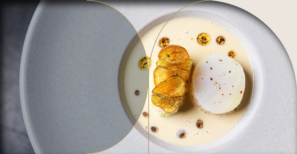 Langwerpig opgemaakt gerecht met lichte saus op bord.
