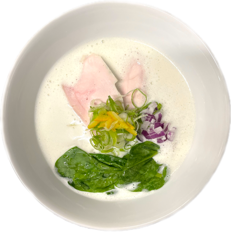 Bovenaanzicht van een kom ramen met lichte bouillon, vlees en groene garnituur.