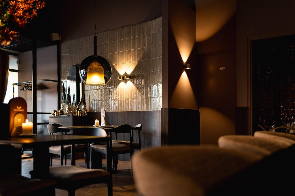 Warm verlichte bistro met tafels en zitbanken.
