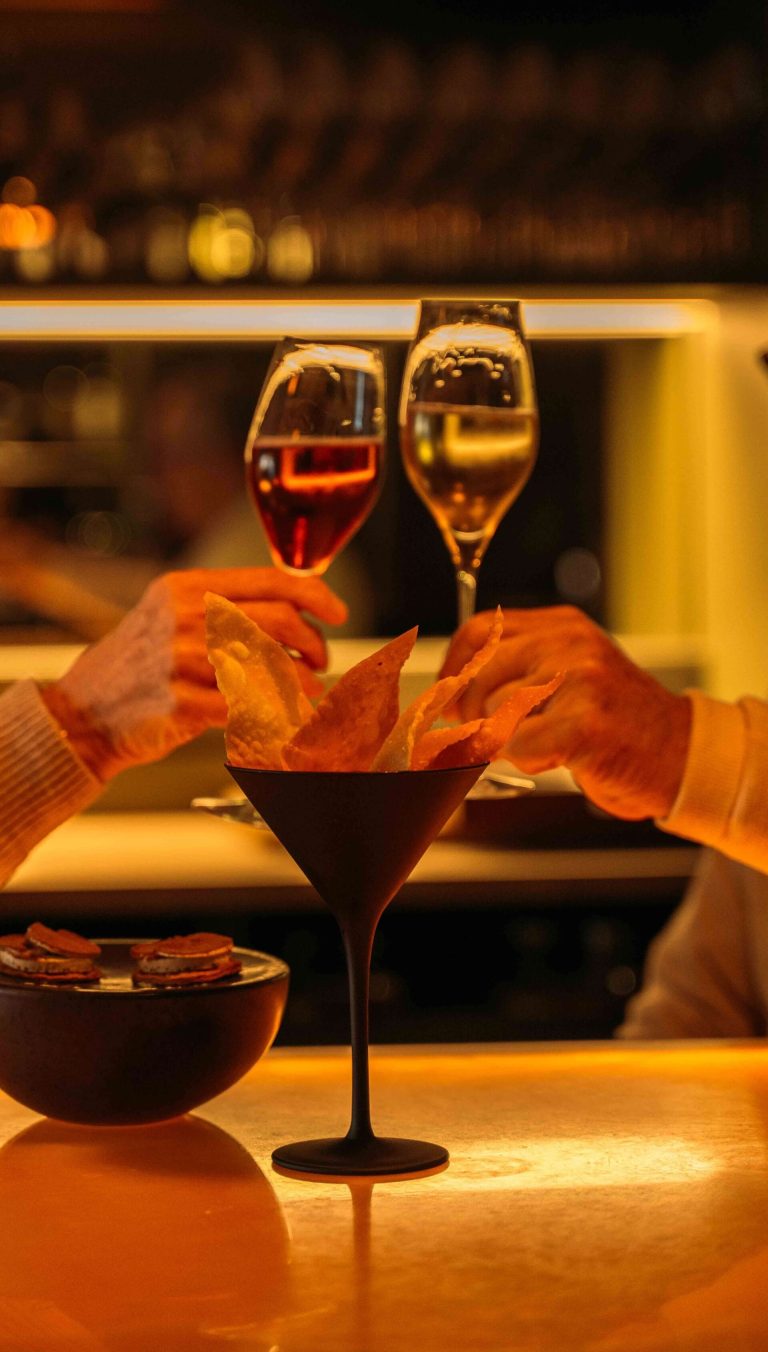 Gasten proosten bij een gedekte tafel met cocktail.