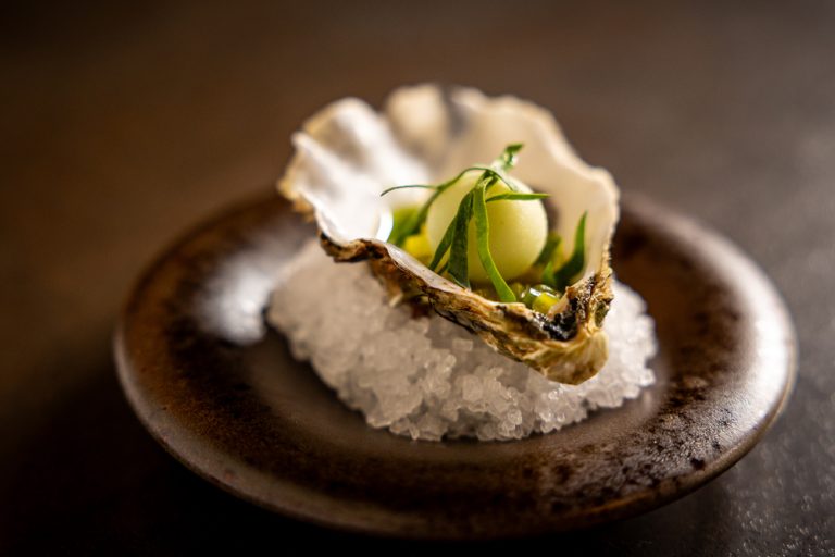 Oester met garnituur op een bed van zout.