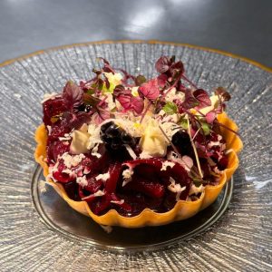 Rond opgemaakt gerecht met kleurrijke garnituur op glazen bord.