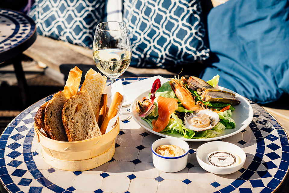 Brood en warme lunchgerechten op terras aan bistrotafeltje.