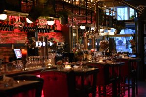 Houten bar met rode accenten en veel glaswerk.