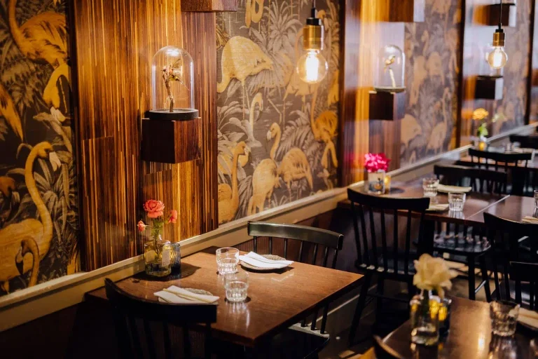 Restaurantinterieur met donkere tafels en Aziatische wanddecoratie.