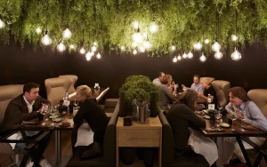 Restaurantzaal met gasten onder groen plafond en veel hanglampen.