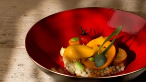 Modern opgemaakt gerecht in groot rood bord.
