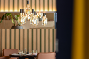 Restauranttafel met kroonluchter en verticale houten wandbekleding.