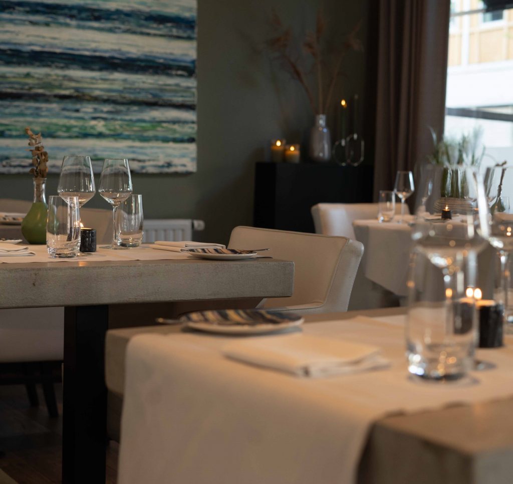 Gedekte restauranttafels met kunst aan de wand.