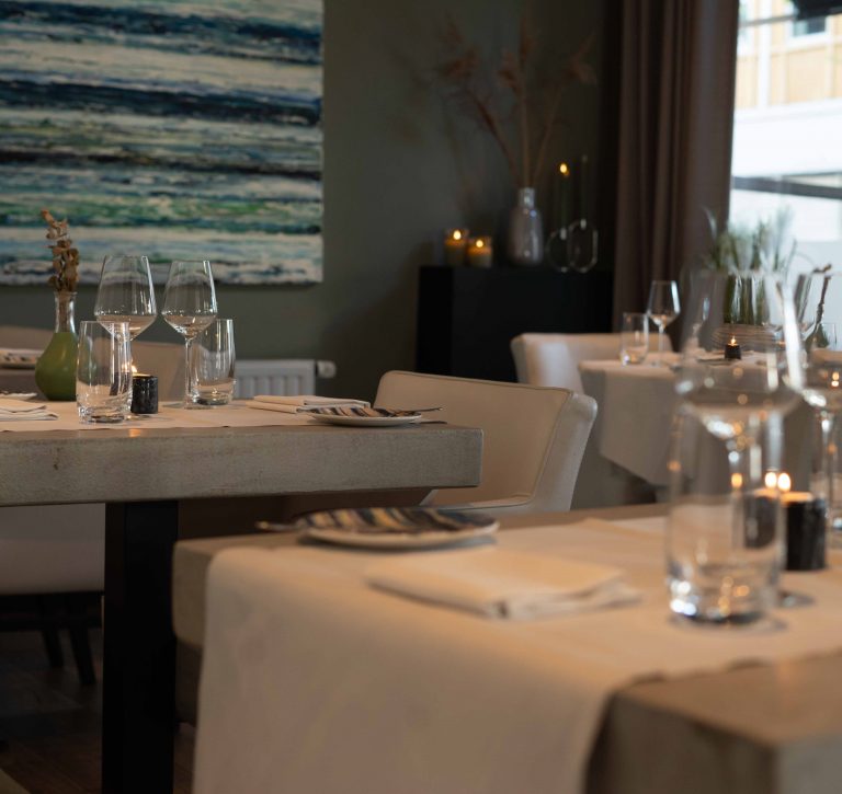 Gedekte restauranttafels met kunst aan de wand.