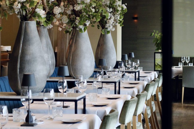 Gedekte tafels met bloemen in restaurantzaal.